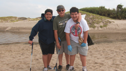 Three happy youth volunteers posing on beach
