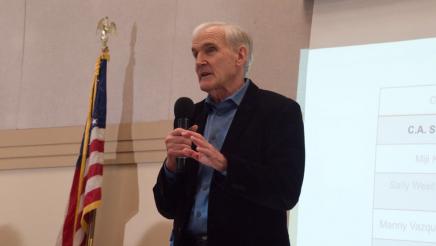 Asm. Bennett holding microphone, speaking
