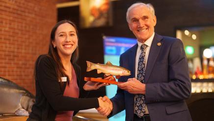 Asm. Bennett receiving salmon award and shaking hands with presenter