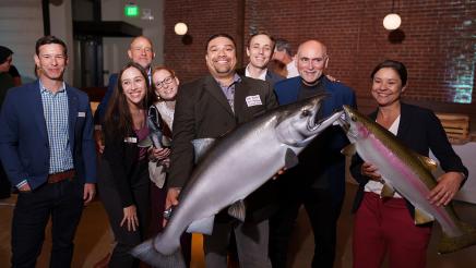 Group photo of attendees; two holding large salmon models