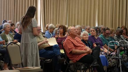 Office Assistant Taylor Spira receiving question from audience member.