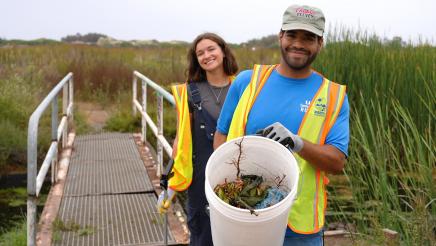 Constituents pose with trash and invasive plant removal